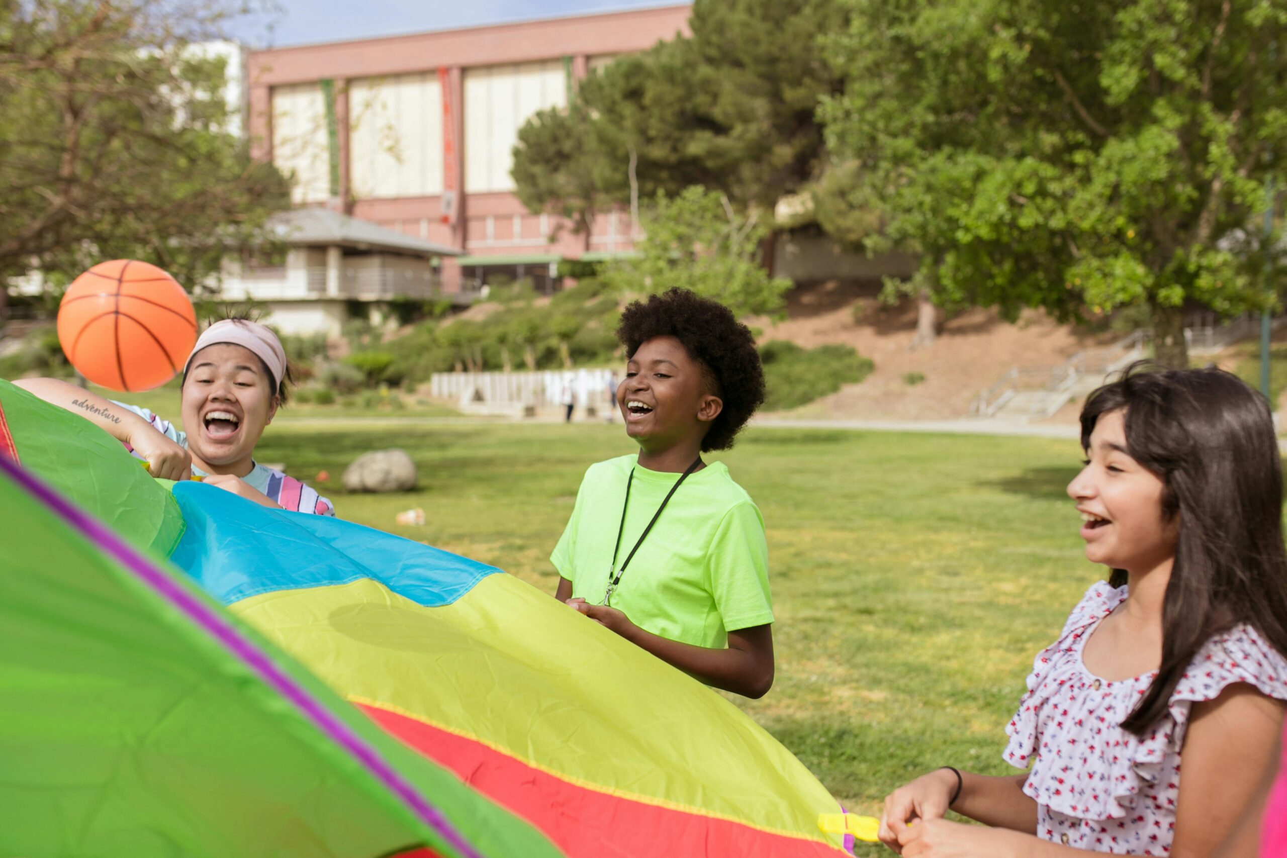 Children having fun with a colorful parachute in a park on a sunny day.